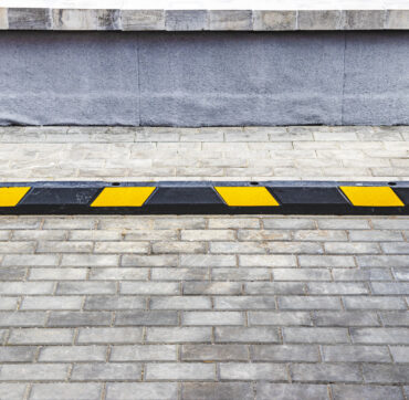 An empty parking lot in a residential area with yellow parking stops for cars. close-up. Stop Parking Limiter