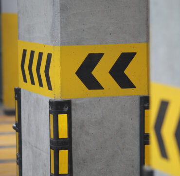 Yellow and black markings on concrete pillars in a parking garage.
