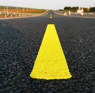 Yellow road markings on asphalt road close up photo